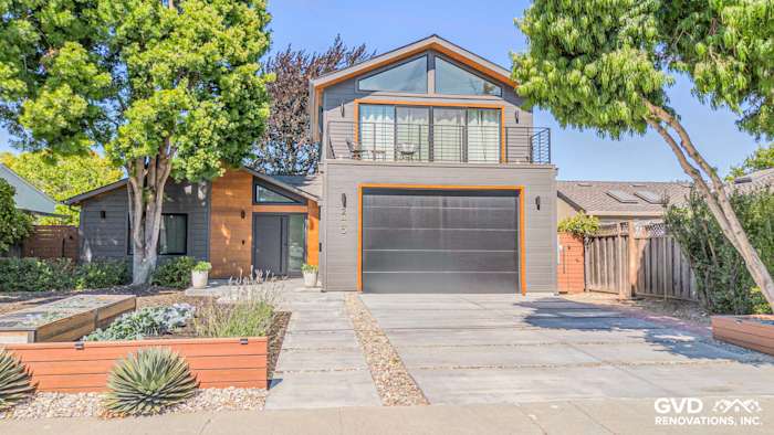 Modern home exterior featuring James Hardie V Groove Artisan Siding in gray, with orange accents and landscaped walkway