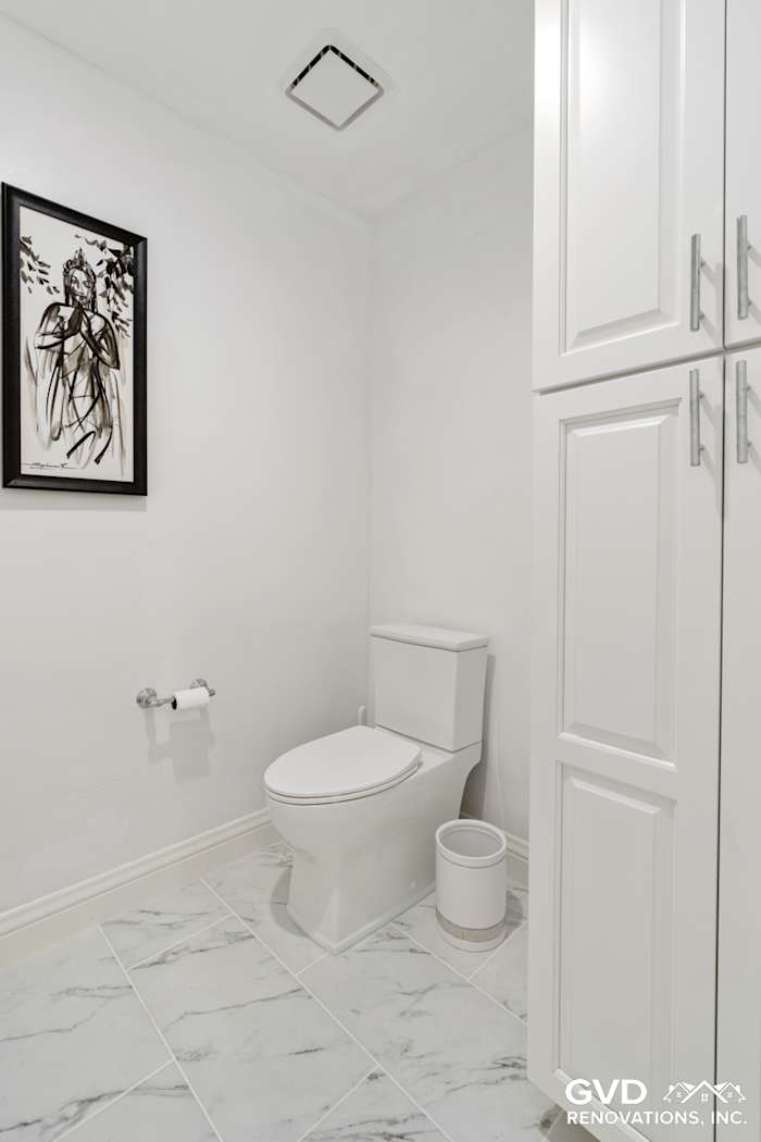 Modern bathroom featuring white cabinetry, marble-look tile floor, and contemporary toilet in Fair Oaks, CA