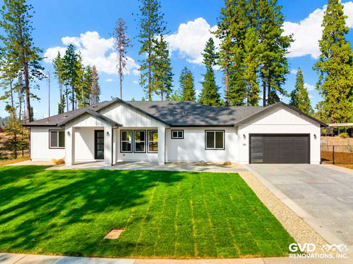 Modern new construction home in Paradise, CA with white siding, black accents, and lush green lawn