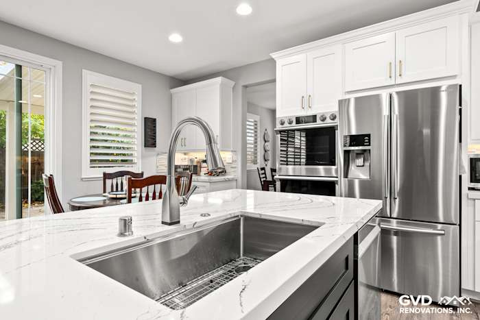 Modern kitchen with Cambria countertops, stainless steel sink, custom white cabinets, and sleek appliances