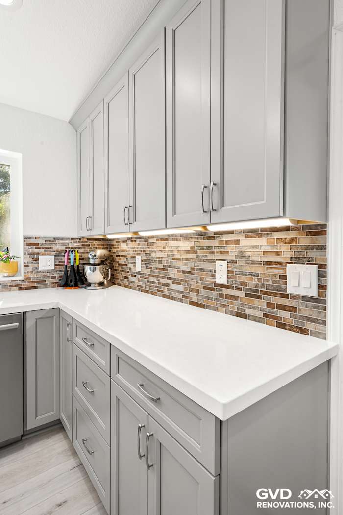 Modern kitchen remodel in Greenwood featuring gray cabinetry, quartz countertop, and mosaic tile backsplash