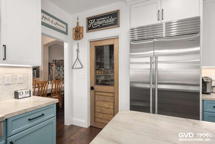 Modern kitchen remodel in Roseville featuring blue cabinetry, quartzite countertops, and a stylish wooden pantry door