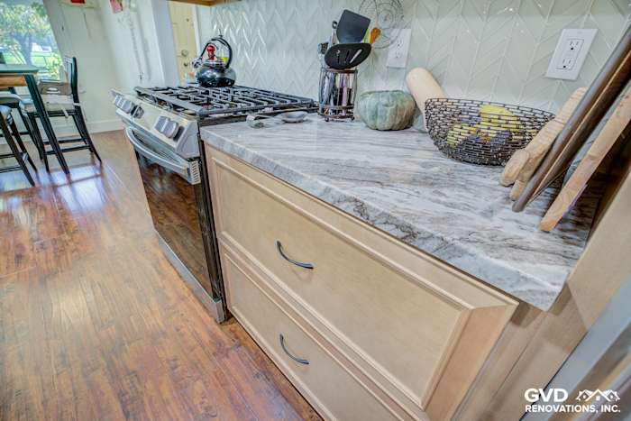 Modern kitchen featuring a gray marble countertop, stainless steel stove, and wooden cabinetry in Sacramento remodel
