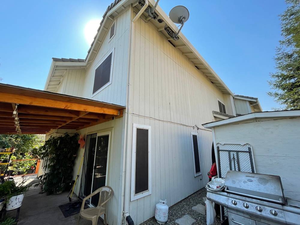 Two-story home exterior with light-colored siding and a large wooden patio in Sacramento