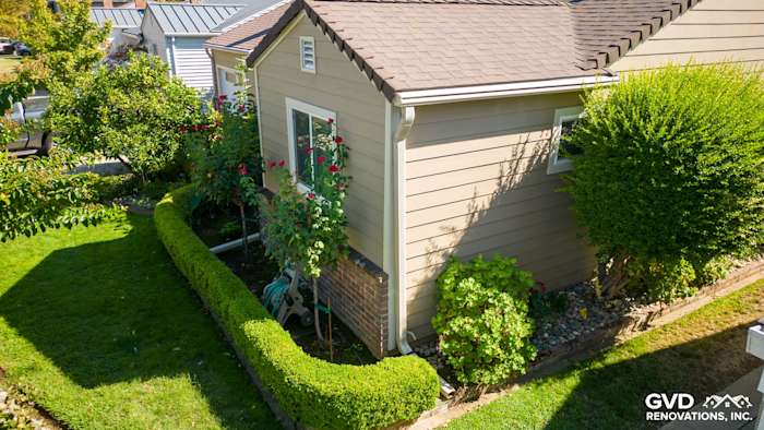Side view of home featuring Khaki Brown James Hardie siding, manicured lawn, and garden landscaping