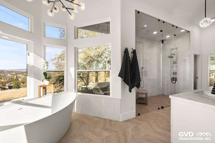 Luxurious bathroom with freestanding BainUltra tub, zero-threshold steam shower, and large windows showcasing the view