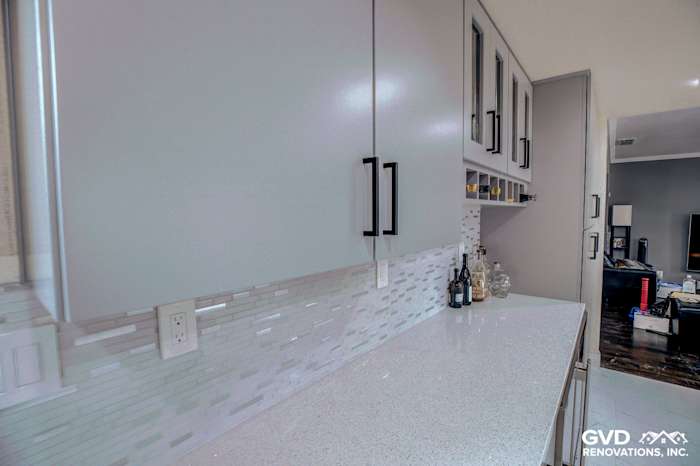 Modern kitchen with white quartz countertop, sleek cabinets, and glass mosaic backsplash in Sacramento remodel