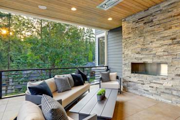 Stylish outdoor lounge with a stone fireplace, comfortable seating, and wooden ceiling in Sacramento