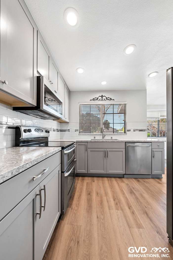 Modern kitchen remodel featuring gray cabinets, quartz countertops, and stainless steel appliances in Carmichael