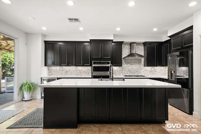 Modern kitchen renovation in Roseville featuring black Waypoint cabinets, white MSI countertops, and a stylish hexagon