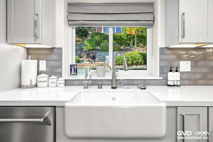 Light gray cabinetry and farmhouse sink with quartz countertop, window view to a landscaped yard in Rocklin kitchen remodel