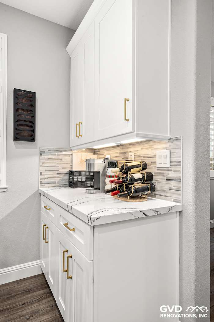 White custom cabinets with gold handles, Cambria countertop, and a stylish wine rack in a modern kitchen