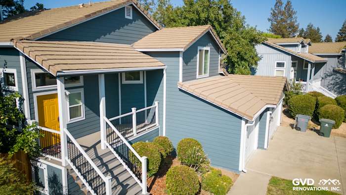 Updated home exterior in Dixon, featuring new blue siding, yellow front door, and refreshed deck with side steps