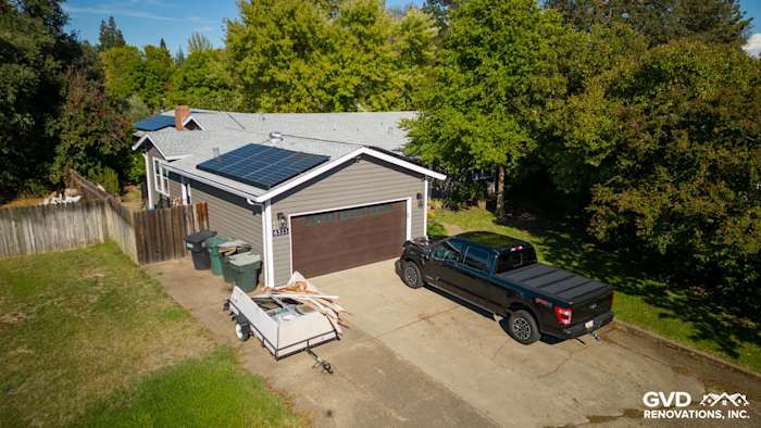 Home exterior featuring new Alside vinyl siding, Milgard windows, and solar panels, set in a green landscape