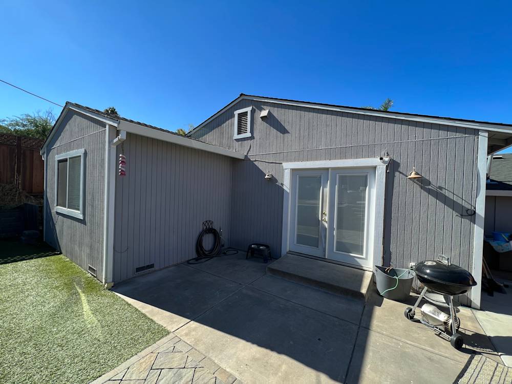 Gray siding exterior of a remodeled home in Sacramento with a concrete patio and sunny sky