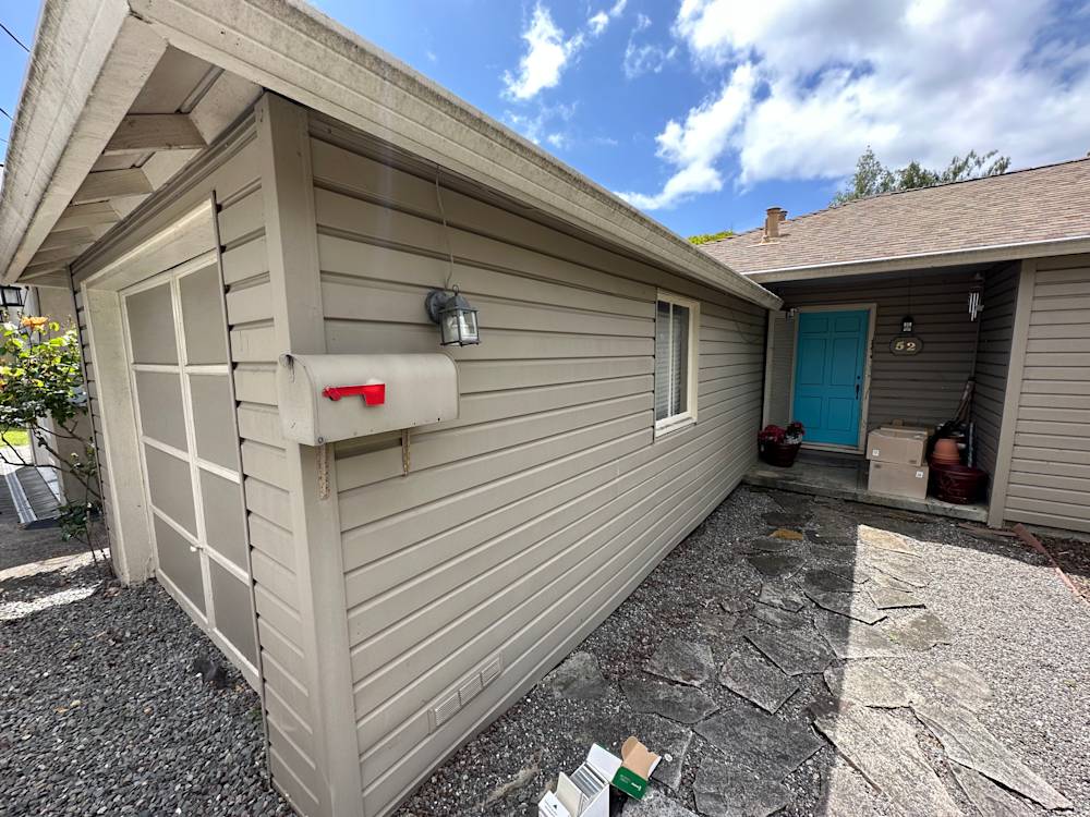 Gray siding and stone pathway leading to a charming turquoise door in Sacramento