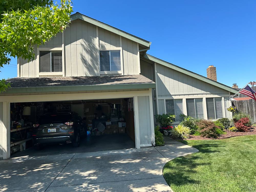 Charming suburban home in Sacramento with gray siding, manicured lawn, and garage access