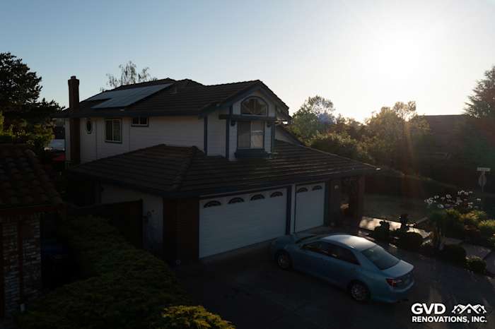 Home exterior featuring James Hardie Arctic White siding and remodeled garage with sunset lighting in Hercules, CA