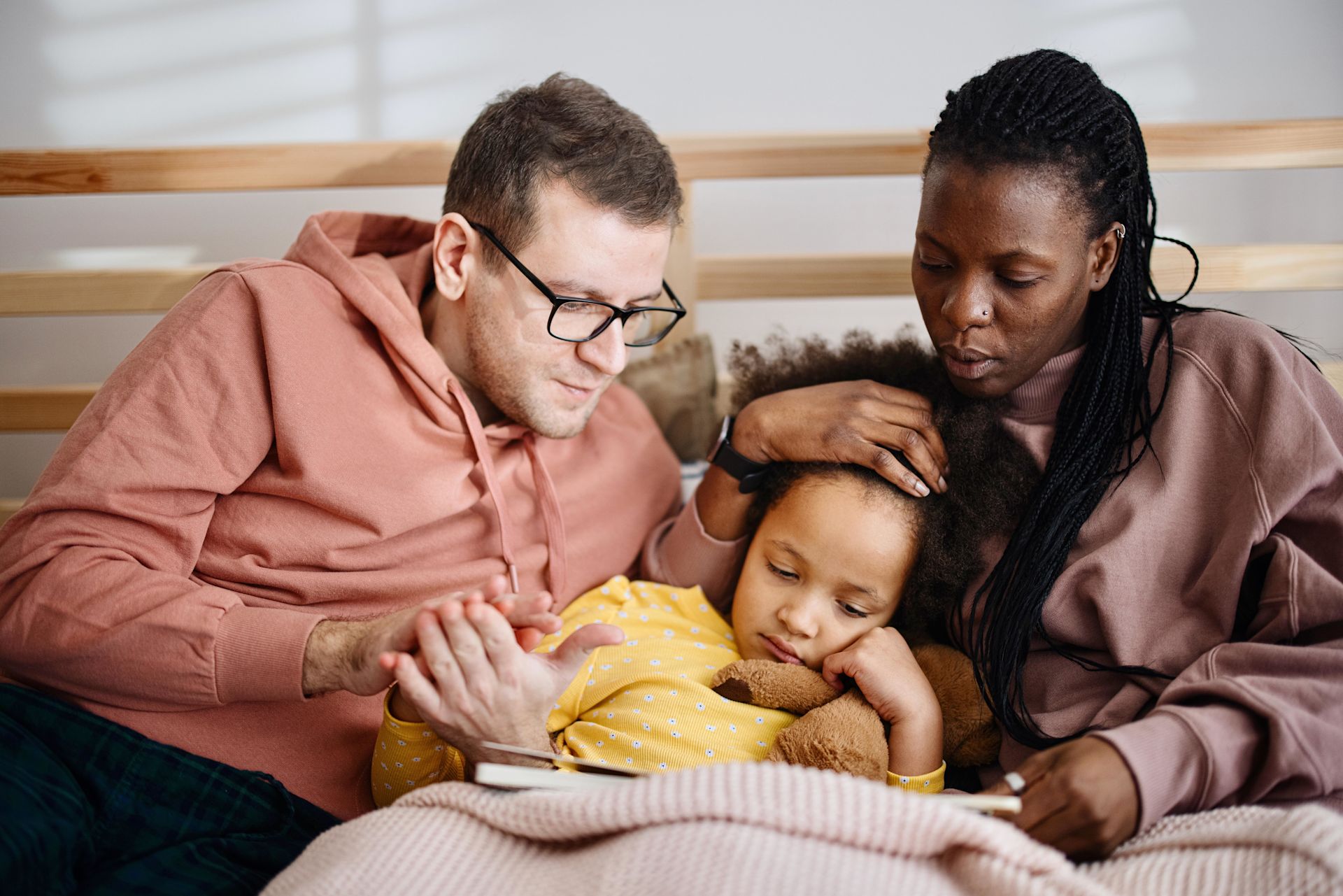 familia con pai, mãe e criança com sinais de constipação sentados num sofá