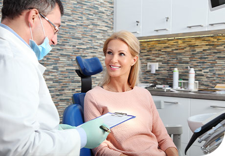 A male dentist explains what is going to happen at the dentist to a female patient who is confident about wearing dentures thanks to Fixodent.