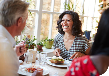 At a dinner party, a woman across the table from a man asks him some frequently asked questions about eating with dentures after recently getting some herself. 