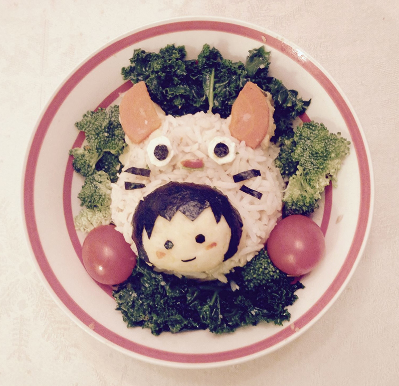 Girl with cat costume food art made of rice, nori, mashed potatoes, and tomatoes.