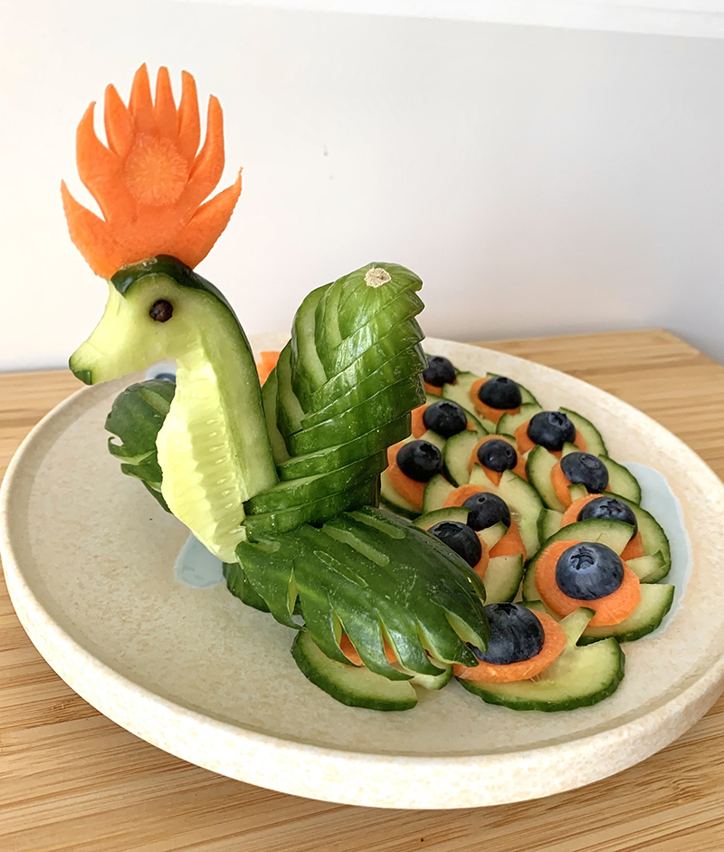 Peacock, made with cucumbers, carrots, blueberries, and a peppercorn.