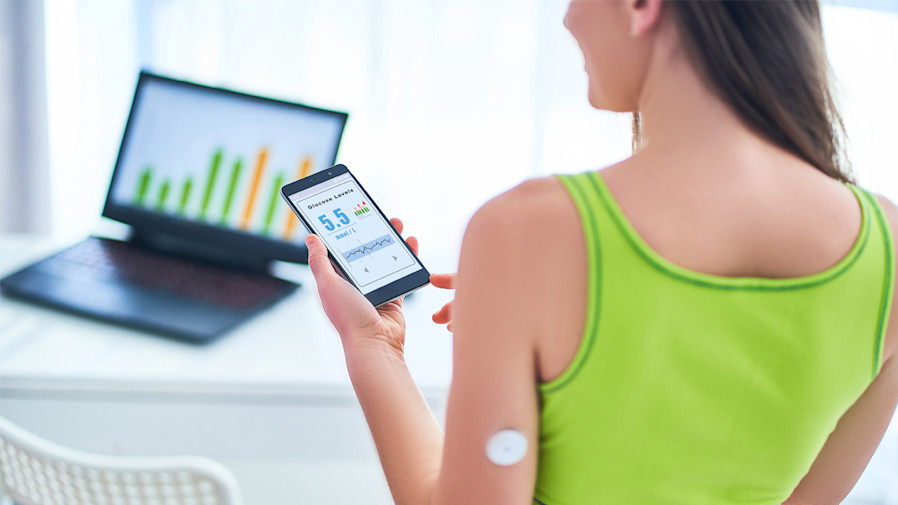 Women interacting with an app on her phone that's connected to her continuous glucose monitor