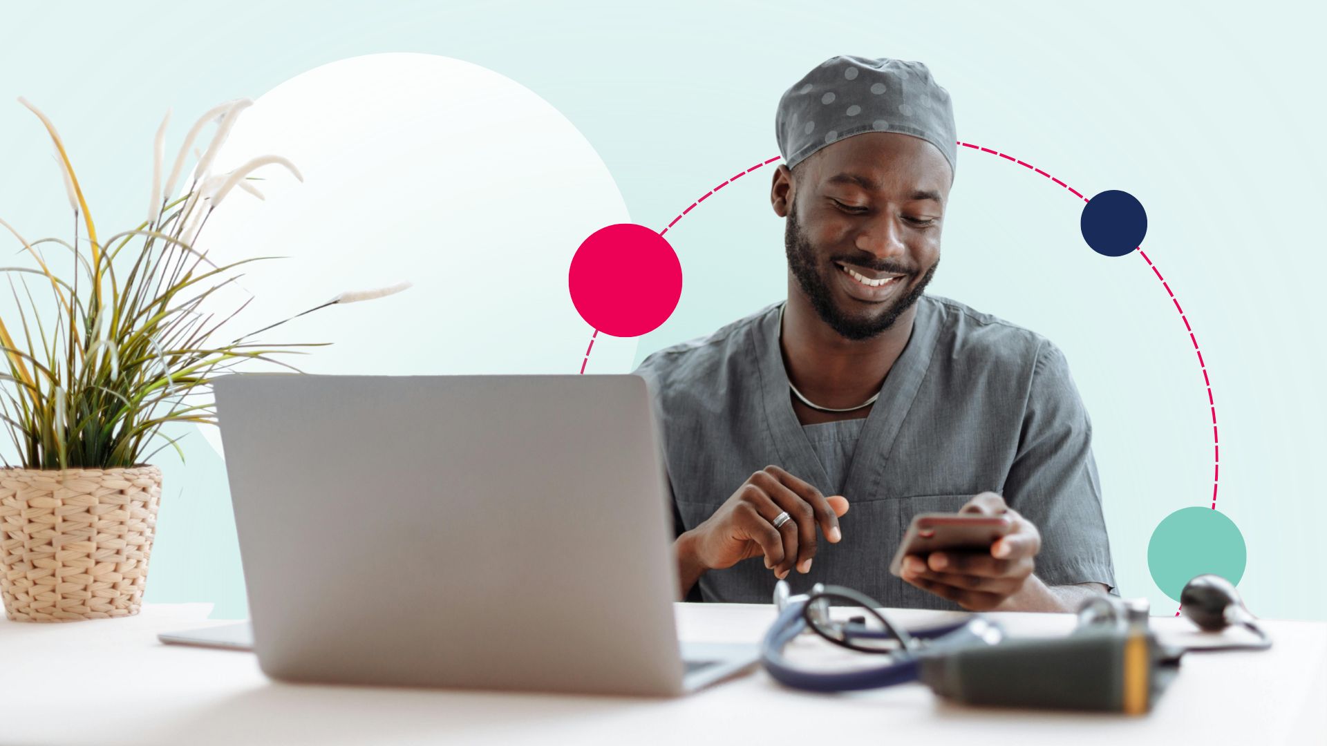 male nurse sitting at a desk on his laptop and smiling