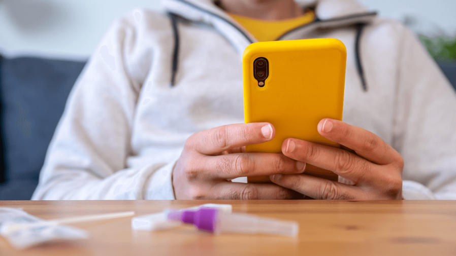 Man holding a phone with used diagnostic tests on the table