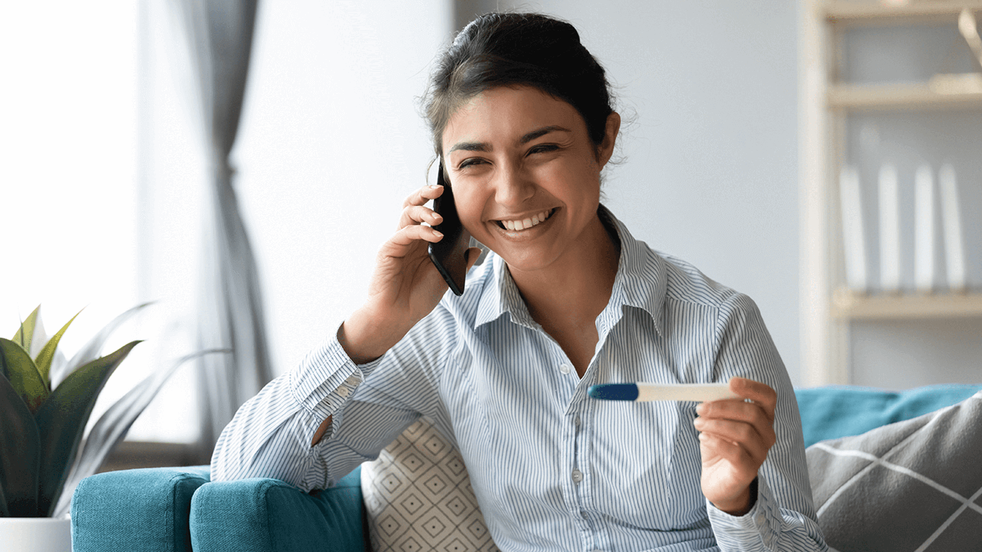 Young-woman-on-the-phone-holding-pregnancy-test