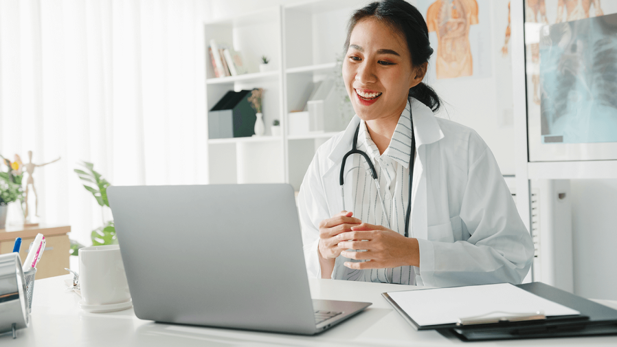Asian, female physician smiling while on virtual care call with patient