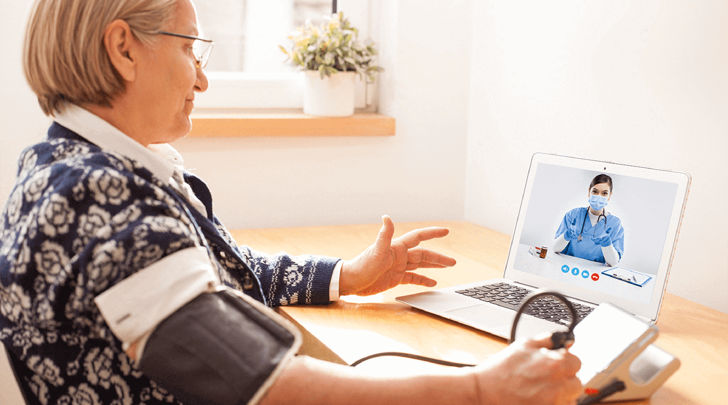 Healthcare-provider-aiding-patient-via-telehealth-monitor-blood-pressure