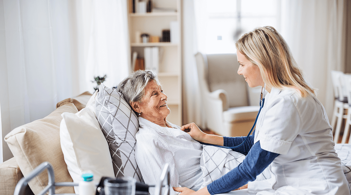 sick-old-woman-in-bed-with-skilled-nurse-checking-heartbeat