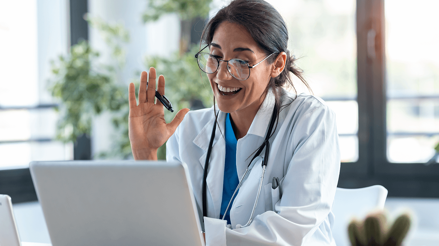 female doctor smiling and greeting patient on video call