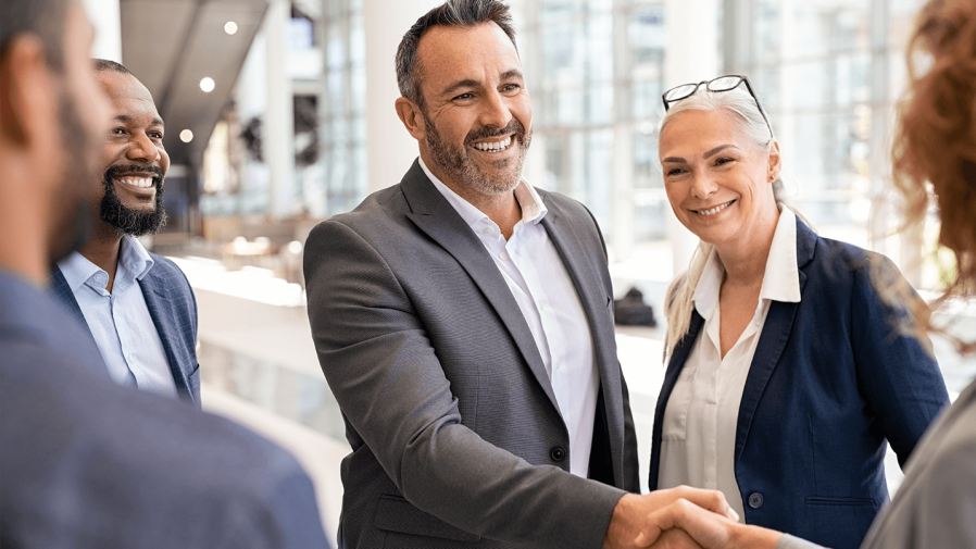 business man smiling and shaking the hand of a business woman after making a deal