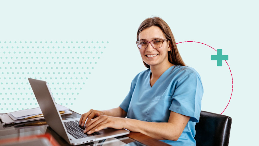 female physician sitting at a desk typing on her laptop and smiling