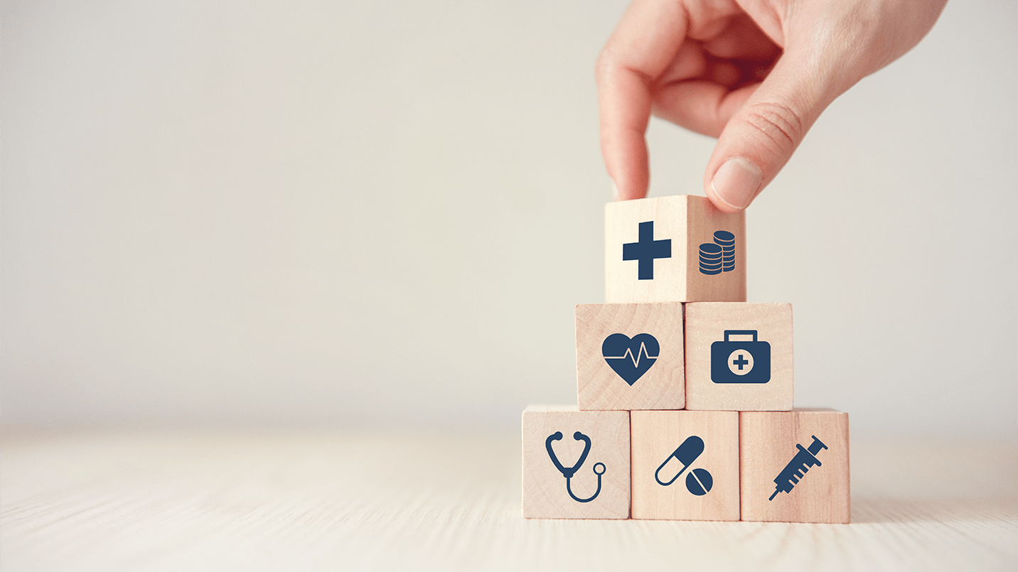 small wooden blocks being stacked in a pyramid with healthcare icons on them