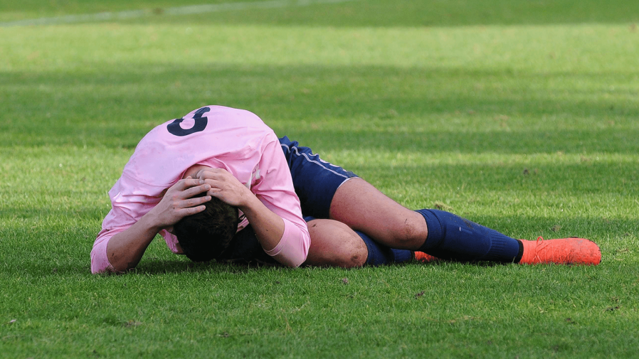 Soccer-player-hunched-on-the-ground-with-a-head-injury