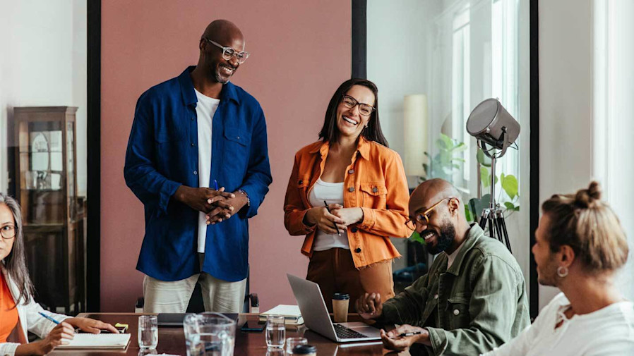 co-workers standing, sitting and chatting around a table in an office