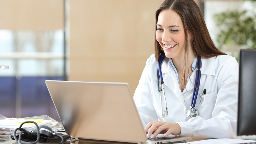 smiling-white-female-physician-typing-on-laptop