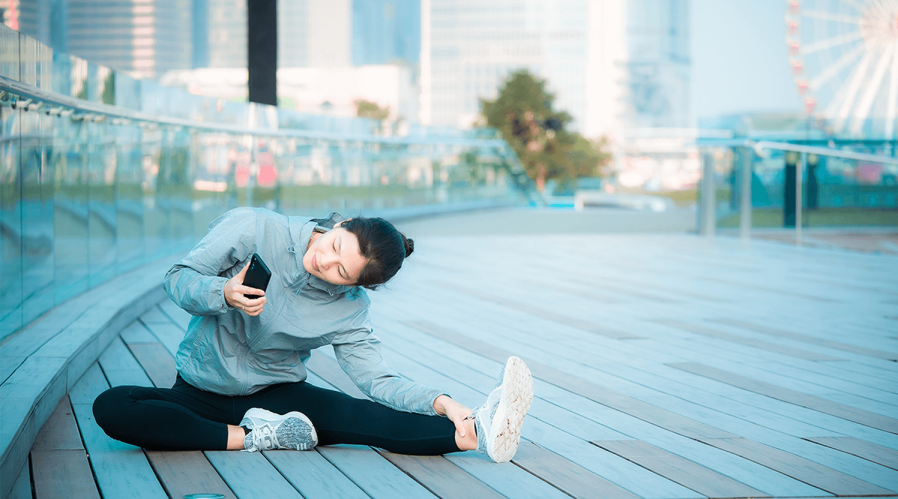 teenage-girl-stretching-outside-looking-at-phone