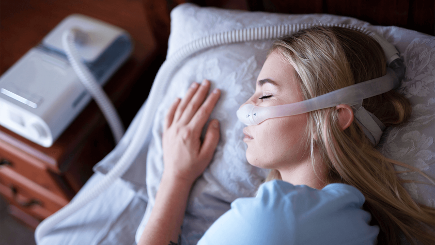women is sleeping in bed on her side with CPAP machine on