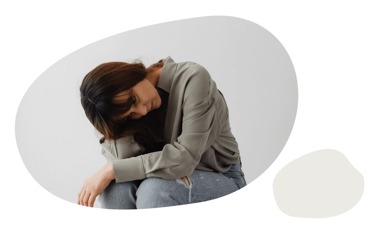 A picture of a woman with her head down experiencing Premenstrual Dysphoric Disorder (PMDD)