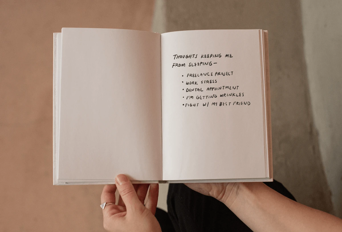 Woman's hands holding a sleep journal with writing. 