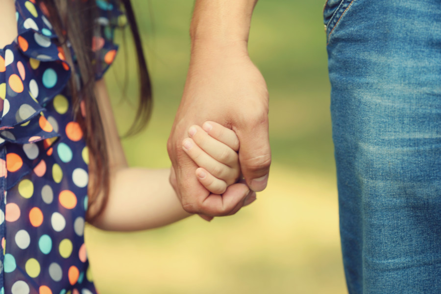 Close-up of a parent holding a child's hand.