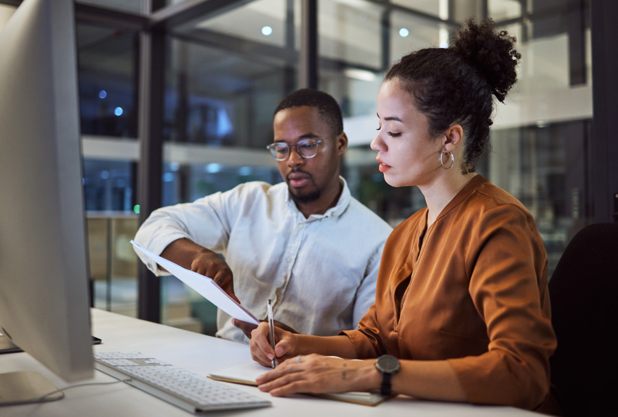 Two workers sitting in an office discussing a document. 