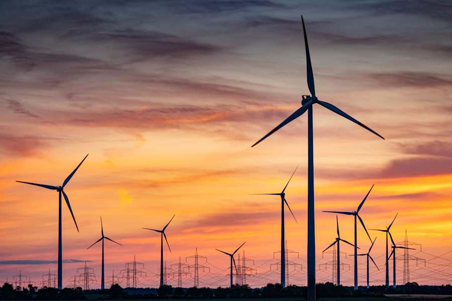 Wind turbines in a green field at sunset