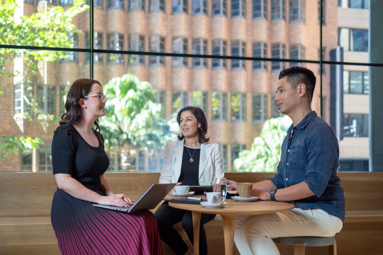 Three colleagues talking in a meeting over coffee