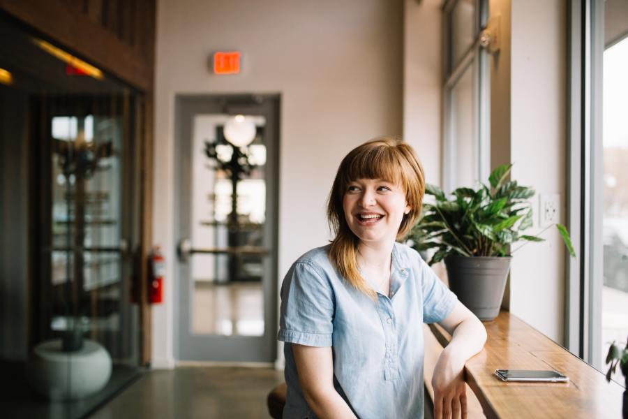 Woman sitting by a counter and smiling into the distance.